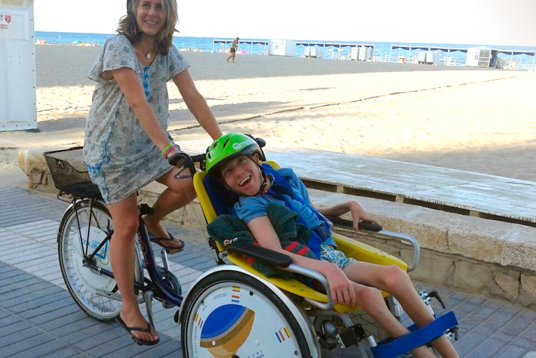 Mujer con bicicleta llevando a una silla de ruedas